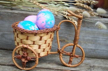 Eggs for Easter in a blue basket on a wooden background close-up with the addition of ears