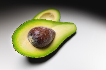 Avocado on old wooden table.Halfs on wooden bowl. Fruits healthy food concept.