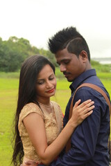 Fototapeta premium A loving young couple on a beautiful green background. Their clothes are made of blue and red