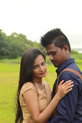 A loving young couple on a beautiful green background. Their clothes are made of blue and red