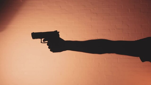 Silhouette of arm raising a pistol hand gun 
