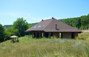 abandoned construction of country modern house. Cottages, townhouses and row houses. Unfinished private house on a construction site. the area around the house is overgrown with grass