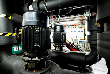 Pump station in the underground premises of the factory, heat station and water treatment facility, pumps and valves, black pipelines