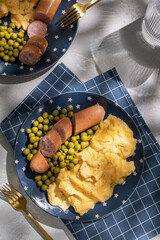 Breakfast with scrambled egg, sausages and green peas