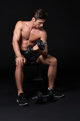 Fototapeta na wymiar Strive for strength. Studio shot of a young man working with dumbbells isolated on black.