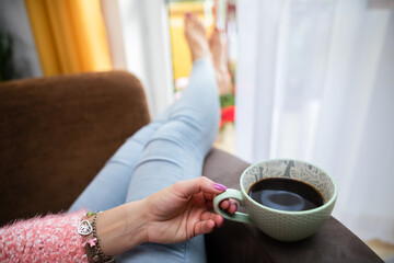 A woman's hand holds a large mug of fresh coffee.