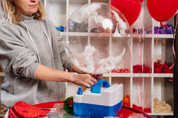 Woman aerodesigner stretches air clear balloon with white feathers inside