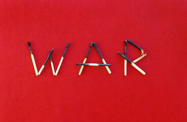 Angebrannte Streichhölzer, die das Wort WAR bilden, auf einem roten Papieruntergrund