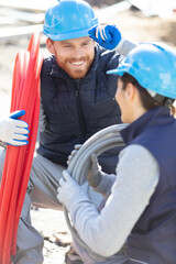 portrait of plumbers with pipes on construction site