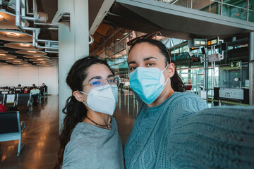 A couple of young LGTB girls taking a selfie at the airport with a mask. Travel concept. Pandemic concept.