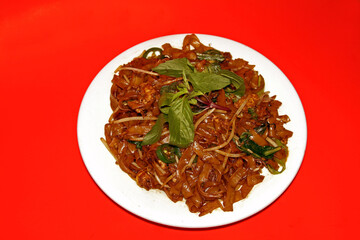 Kweetiau Goreng Chinese, Indonesian food on a red tablecloth background. Close up.