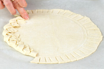 Pizza making process. Top view of pizza dough base. Home-baking pizza with a braided pie crust. close up