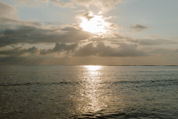 Nascer-do-sol entre muitas nuvens e  lindo mar iluminado pelos raios de sol na orla de Porto Seguro, Bahia.