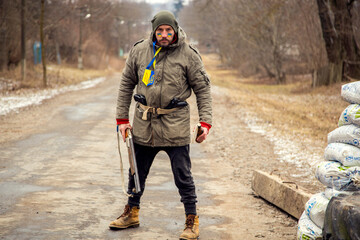Naklejka premium A Ukrainian man with a weapon at a checkpoint. A Ukrainian patriot guards the entrance to his village.