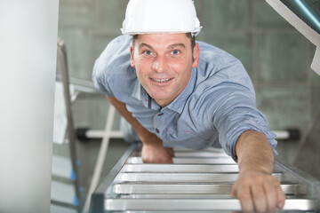 happy male builder standing on ladder