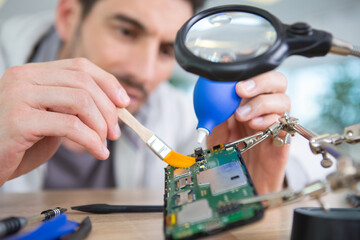 handsome technician cleaning broken electronics