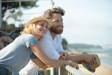 Obraz premium couple are hugging by the wooden fence on the beach