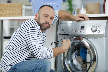 exhausted man by washing machine at home