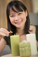 happy young woman lights some candles at home