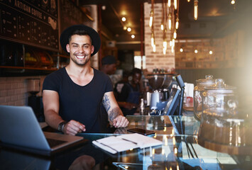 Part of the fun is creating new menus. Shot of a handsome young man working behind the counter of a coffee shop.