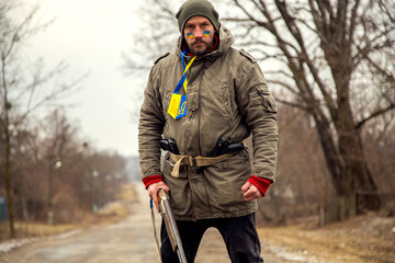 A Ukrainian man with a weapon at a checkpoint. A Ukrainian patriot guards the entrance to his village.