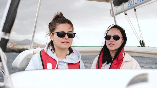 Two skipper woman in sunglasses sailing a boat in sea