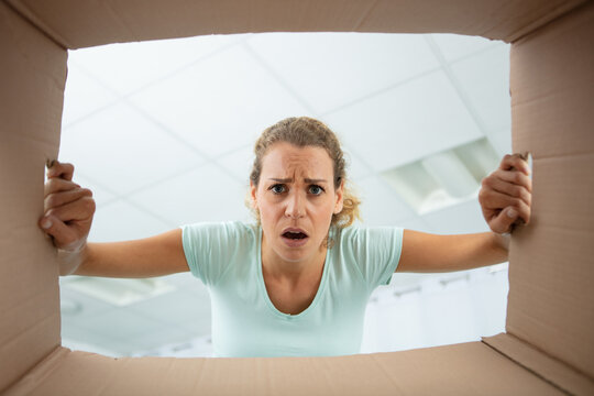 low angle view of disgruntled woman looking into cardboard box