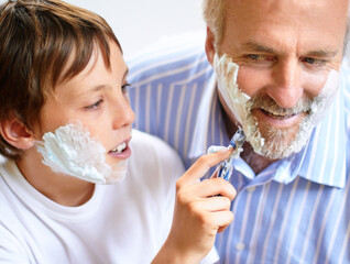 I cant wait to have a beard. Shot of a boy shaving his fathers beard.