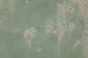 Old weathered painted wall background texture. Green dirty peeled plaster wall with falling off...