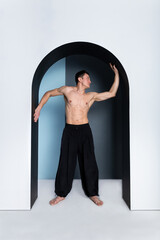 Portrait of a barechested male athlete  stretching arms in studio.