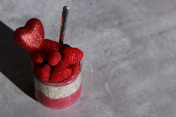 Glasses of chia pudding dessert with raspberry on grey marble table 