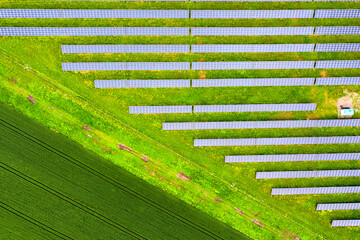 Aerial view of solar power plant on green field. Electric panels for producing clean ecologic energy.