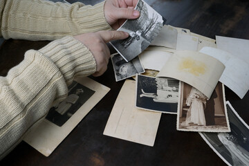 female hands fingering old photos, vintage monochrome photographs 1950, concept of genealogy,...