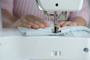 close-up of female hands perform work on a white sewing electric computer machine, stitches appear...