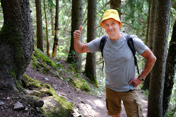 charismatic mature man in panama with backpack walks along mountain path, hiking in forest, active lifestyle of people, mountaineering, via ferrata in mountains, life insurance in extreme sports