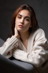 Portrait of a young brunette with long hair in the studio. Dramatic photo in dark colors.