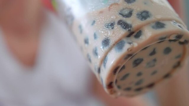 Close up of glass of bubble milk tea in female hand.
