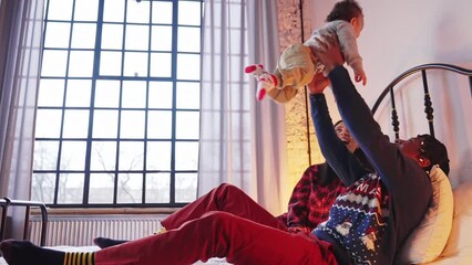 Happy proud father playing with his mixed-race toddler son on a bed. High quality 4k footage