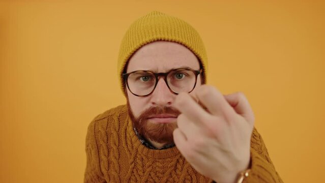 middle-aged bearded hipster man knocking at the screen and suspiciously looking inside, yellow background studio shot. High quality 4k footage