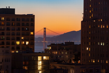 Golden Gate Bridge at sunset seen through buildings, Nob Hill, San Francisco, California