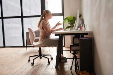 Girl with prosthesis hand sitting at the table at home and talking via video call