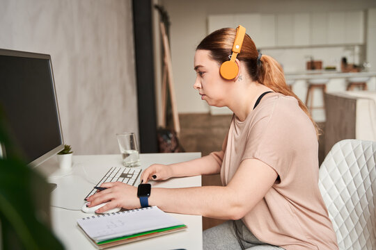 Calm caucasian female with artificial limb sitting at the table with her computer while working