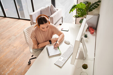 Caucasian female with arm implant sitting at the table with her computer and writing