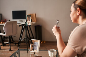 Caucasian blogger talking to camera and showing lushes curler while recording blog about makeup