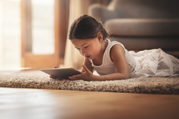 Educational apps right at her fingertips. Shot of an adorable little girl using a digital tablet on...