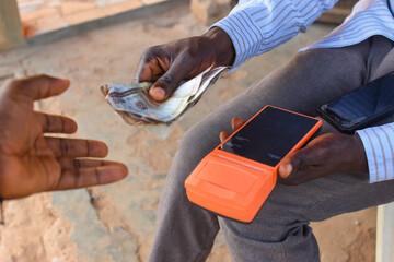 Hands of two african individuals doing financial transaction with a point of sales POS terminal as...