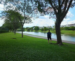 Middle age woman standing alone in a park in front of a lake