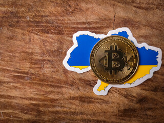 Top view bitcoin and ukraine flag on a wooden background with copy space.
