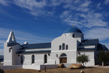White Greek Orthodox church with a blue roof under blue sky