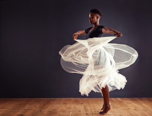 Freedom of expression. Young female contemporary dancer using a soft white white skirt for dramatic effect.
